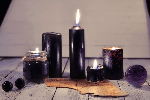 Na imagem, há velas e cristais em cima de uma mesa.