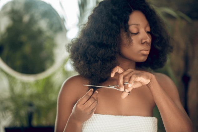 Mulher negra cortando seu próprio cabelo. 