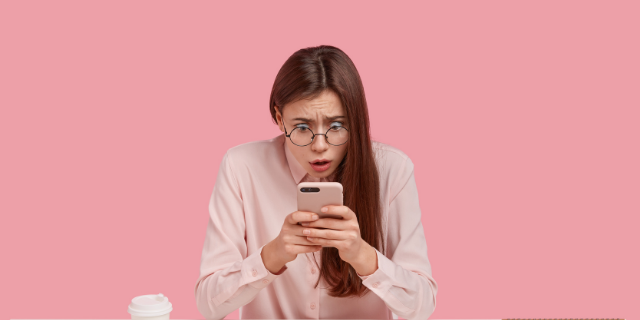 Mulher observa o celular com uma expressão facial aflita.
