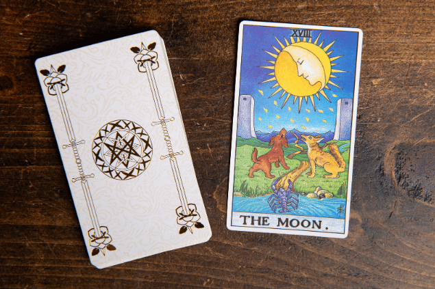 A carta A Estrela do Tarot está sobre uma mesa de madeira em destaque na imagem. Ao lado, há um baralho com outras cartas.