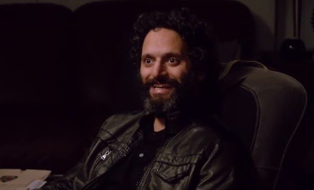 Homem branco de barba e cabelos pretos, usando roupas pretas, com expressão sorridente.