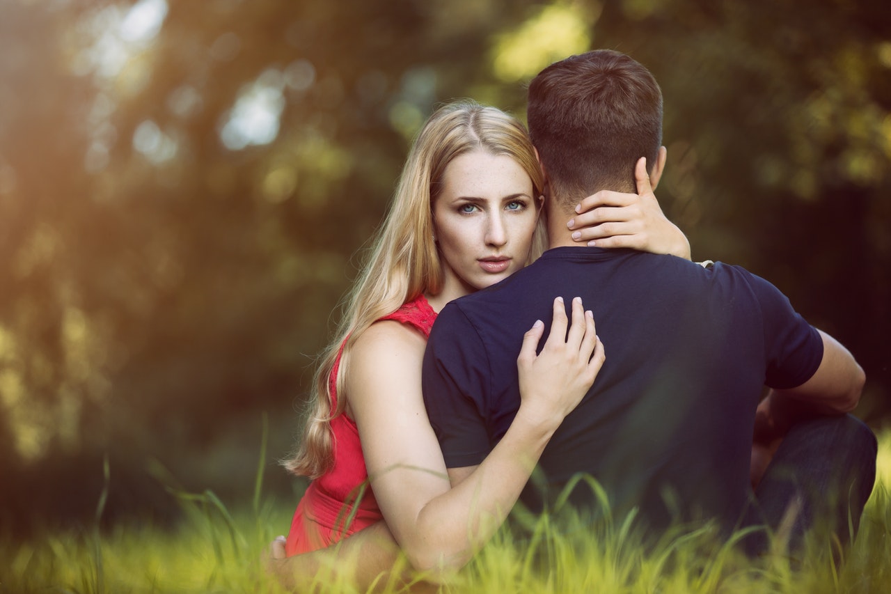 Mulher abraçando homem enquanto olha diretamente para a câmera.