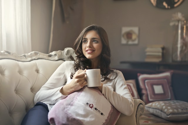 Mulher branca sentada segurando caneca.