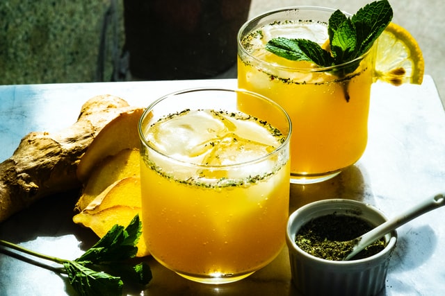 Suco de laranja com gengibre e hortelã em volta.