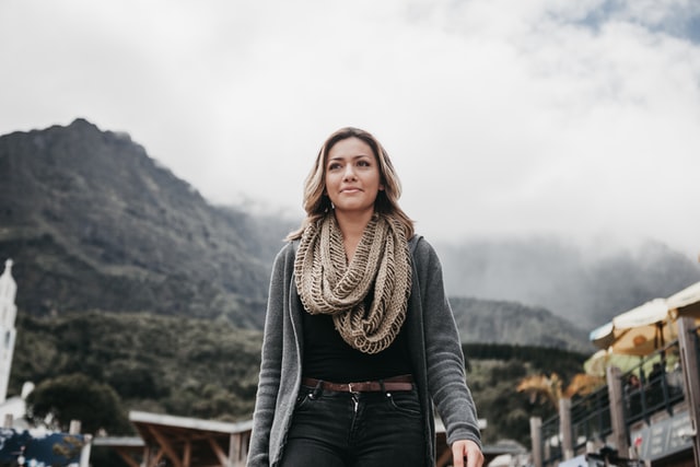 Mulher branca com roupas de frio num campo.