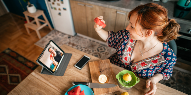 Mulher em vídeo-chamada com um homem. Eles comem frutas. 