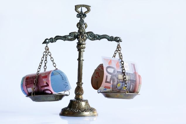 Balança equilibrando notas de dinheiro em seus dois lados.