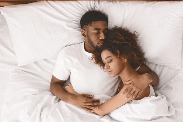 Casal abraçado e deitado na cama