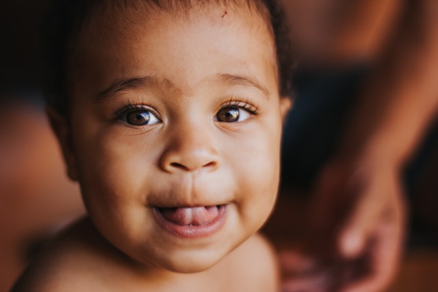 Bebê negro com a língua pra fora.