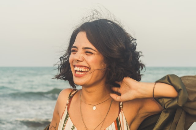 Mulher branca sorrindo na praia.