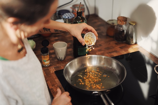 Mulher branca colocando alimenta na panela.