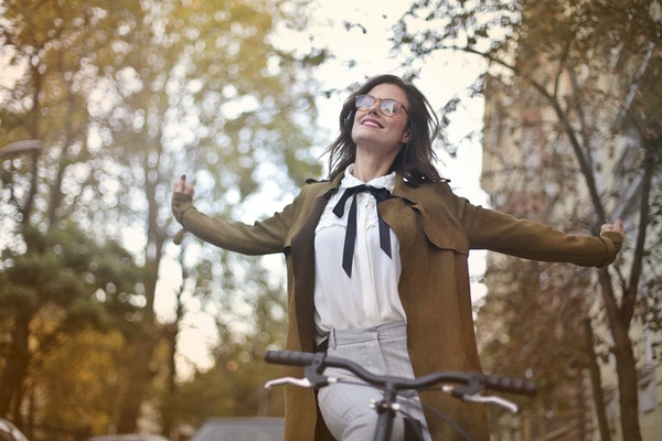 Mulher andando de bicicleta com braços abertos 
