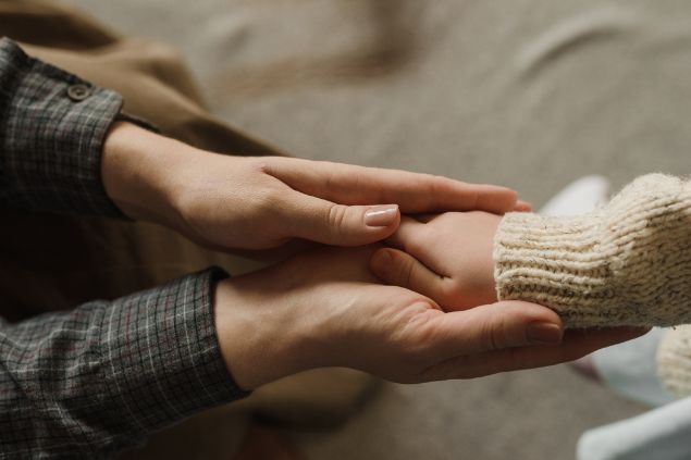 Imagem de mãos adultas em cima das mãos de uma criança