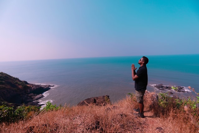 Homem negro em cima de morro rezando.