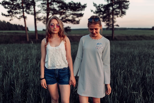 Mulheres brancas e loiras de mãos dadas num campo.