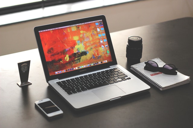 Mesa com notebook, celular, óculos, caderno organizados