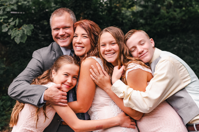 Família de 4 integrantes abraçados