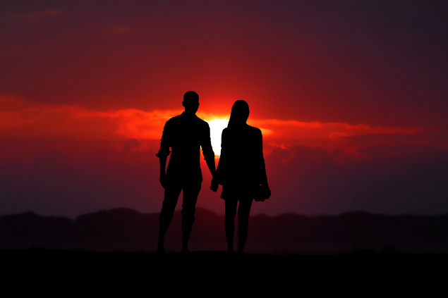 Casal se dando as mãos no pôr do sol