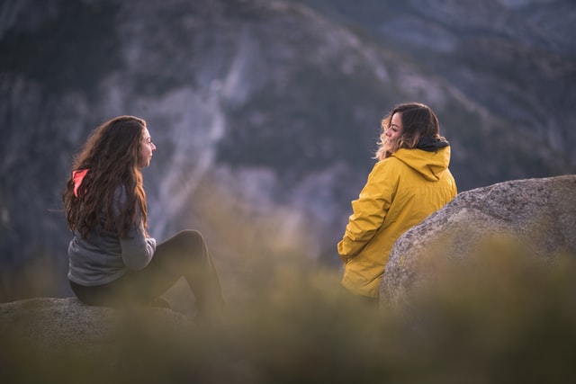 Mulheres brancas sentadas em rochas conversando.