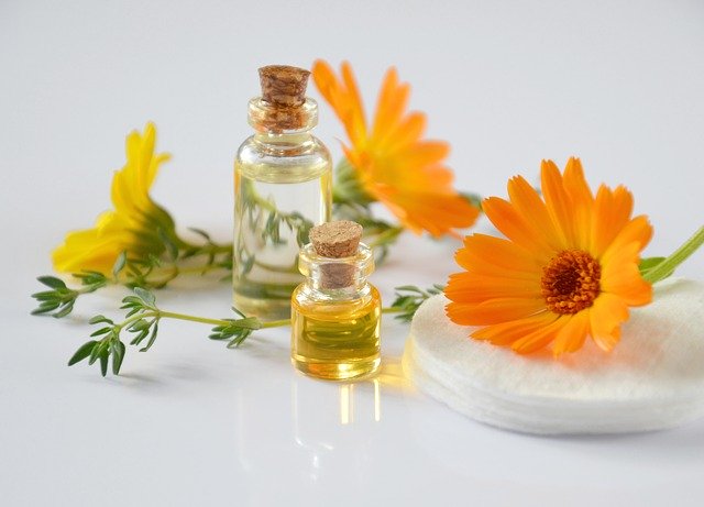 Flores de calêndula e potes com óleo da flor ao lado.