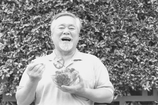 Imagem antiga de um homem velho comendo enquanto sorri