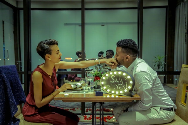 Homem negro beijando mão de mulher negra em restaurante.