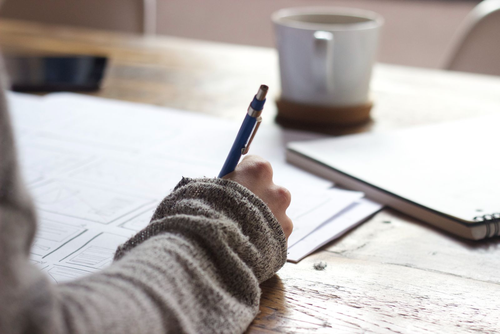 Mulher escrevendo no papel em sua mesa de escritório