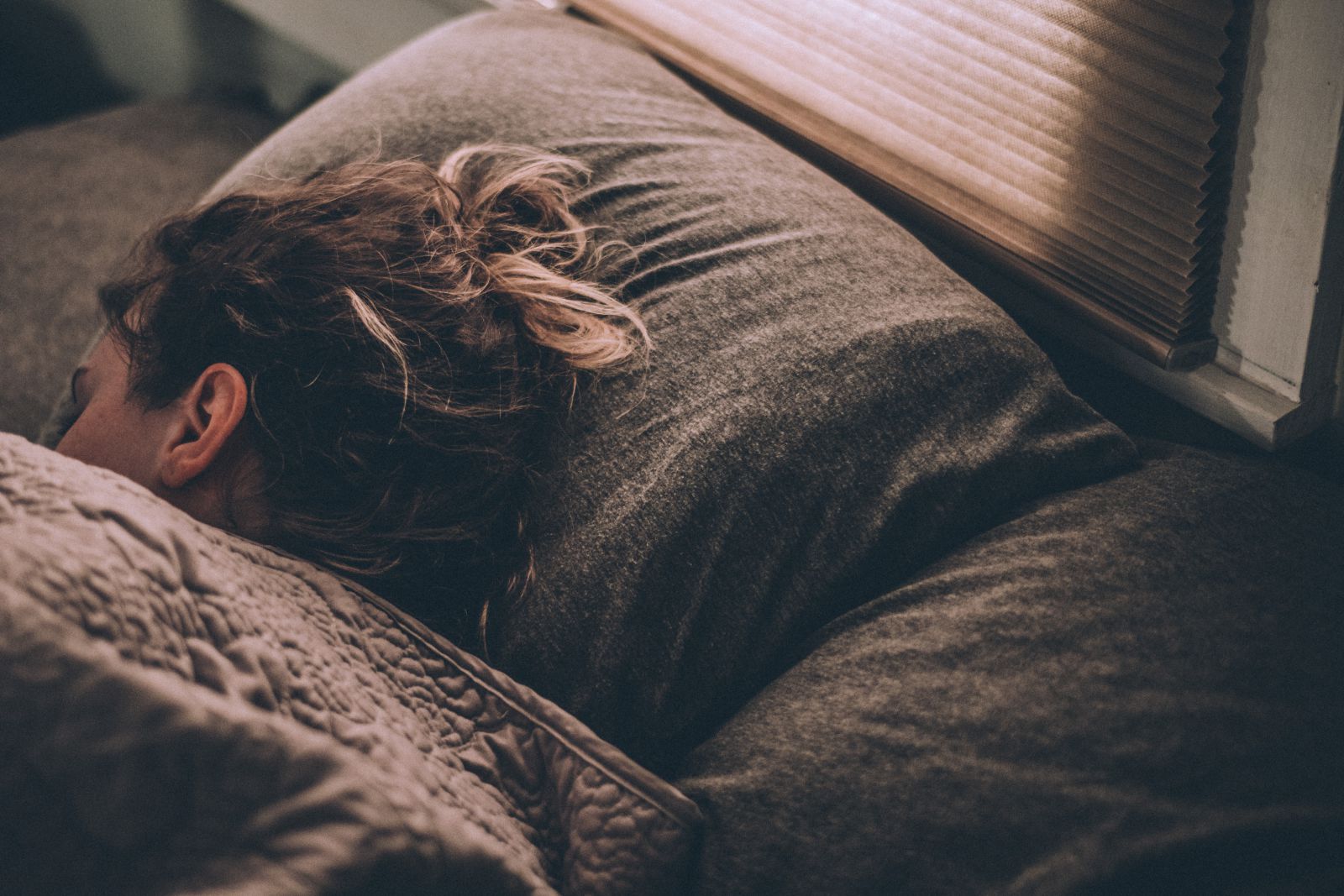 Mulher deitada na cama coberta de olhos fechados 