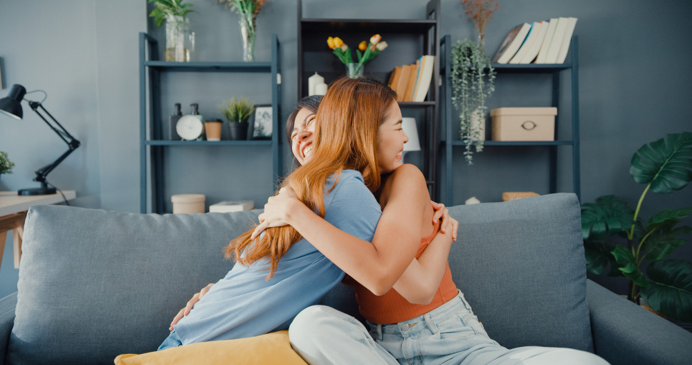 Primas se abraçando em sala de casa