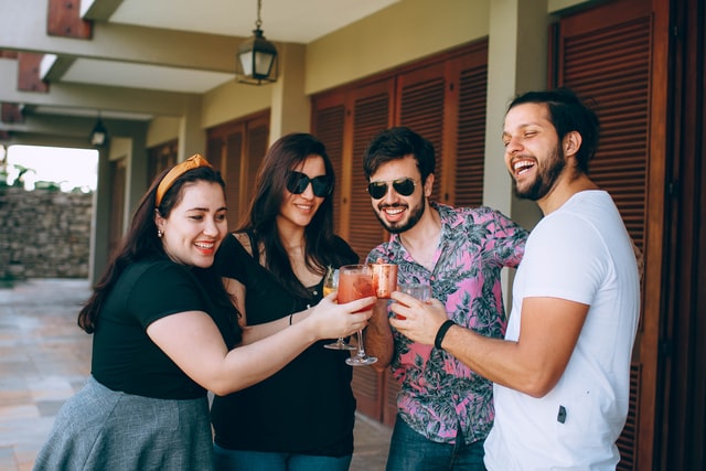 Homens e mulheres brancos brindando copos.