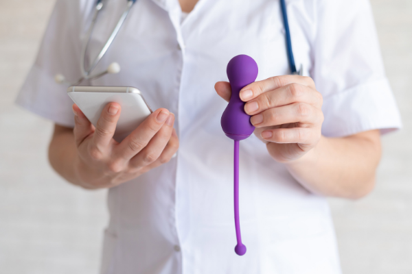 Mulher segurando um celular e utensílio de Kegel