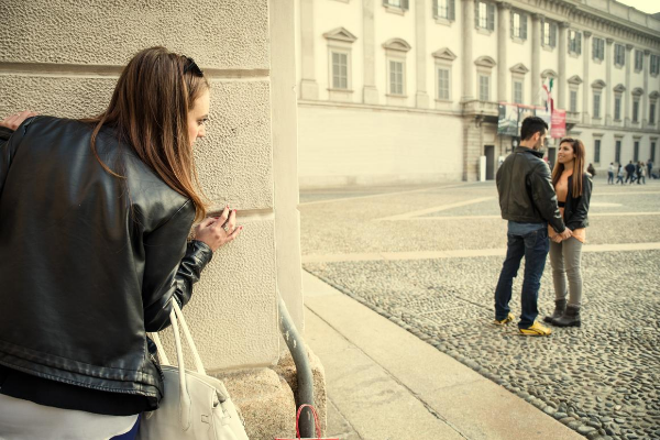 Mulher escondida, observando um casal conversando.