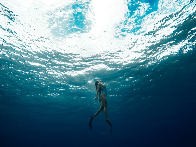 Mulher branca imersa ao mar.