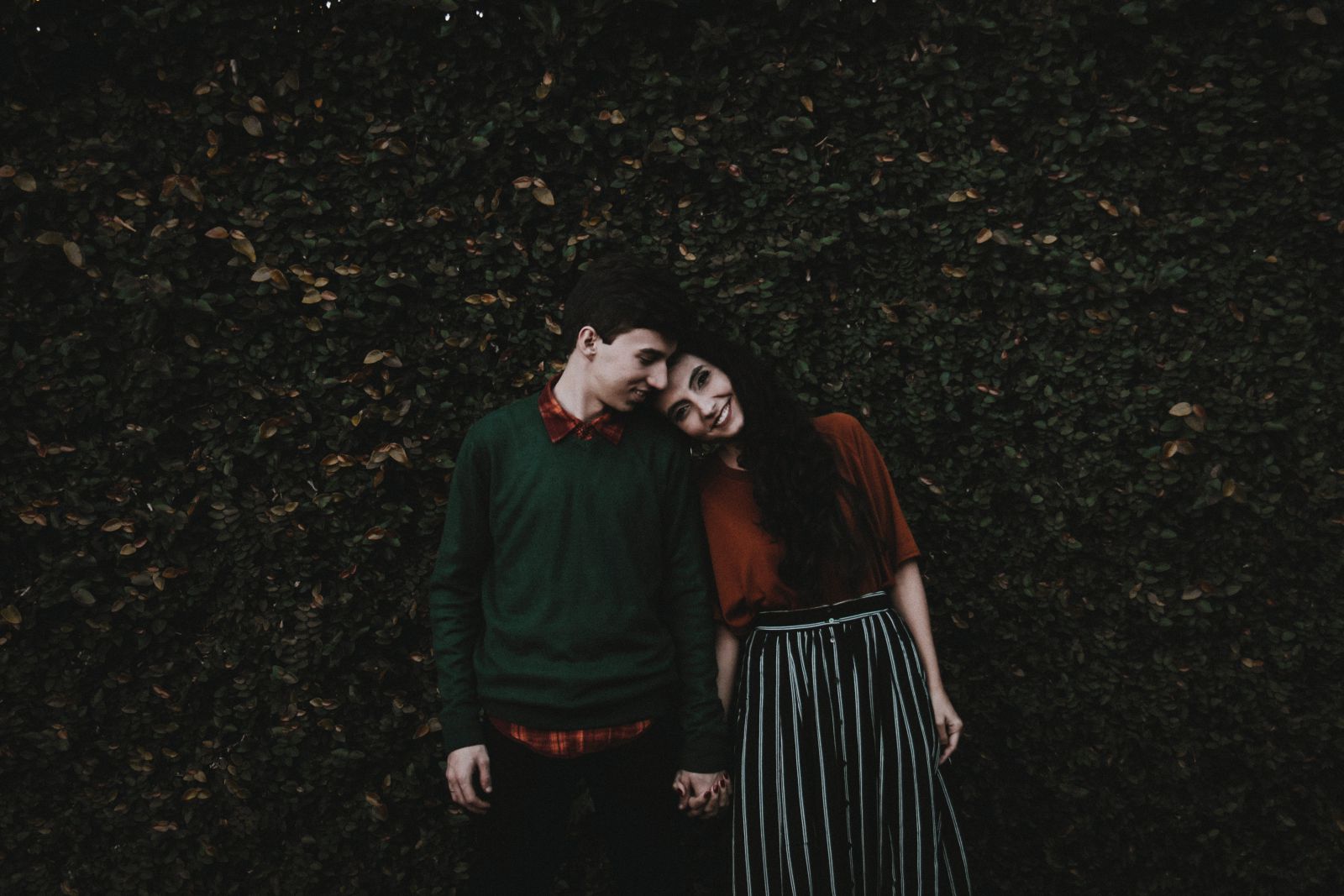 Casal em um jardim sorrindo de mãos dadas