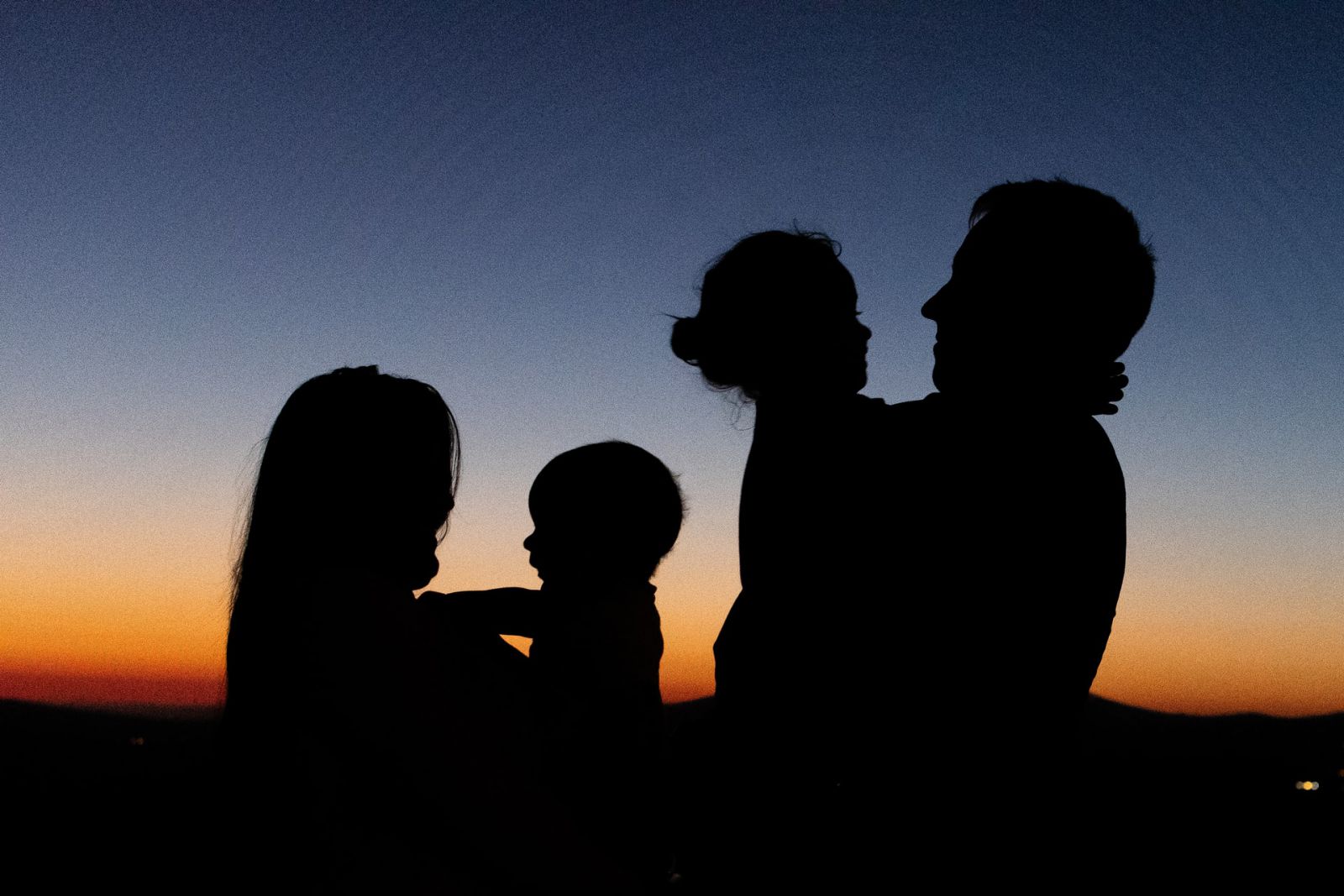 Silhueta de homem e mulher com crianças no colo.