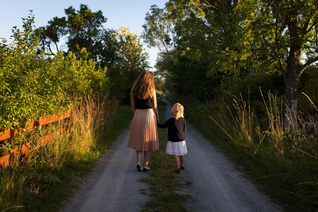 Mulher e crianças brancas de mãos dadas.