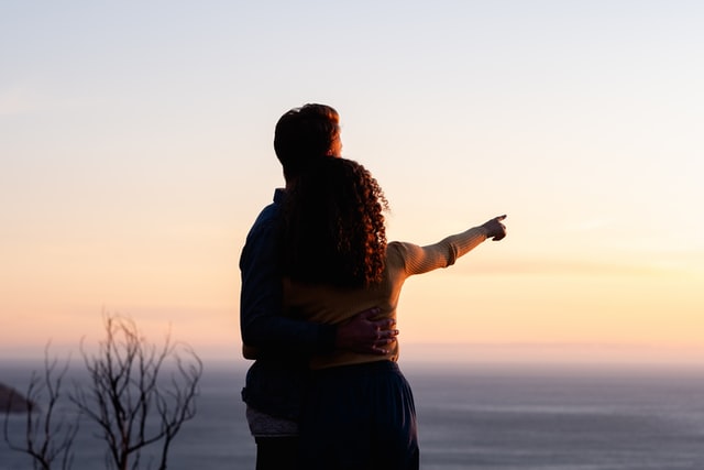 Mulher negra e homem brancos abraçados.