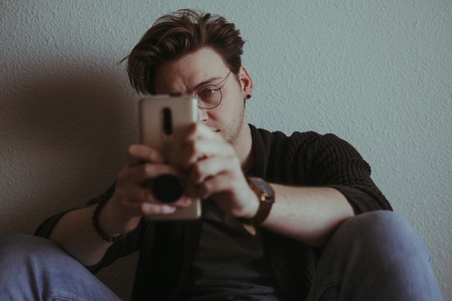 Homem branco segurando celular com expressão brava.