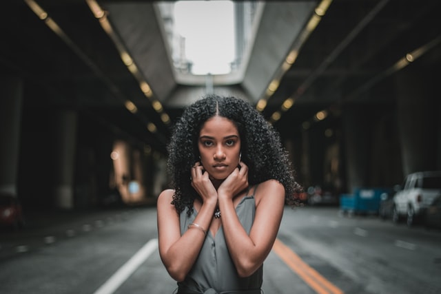 Mulher negra com expressão serena e mão no pescoço.