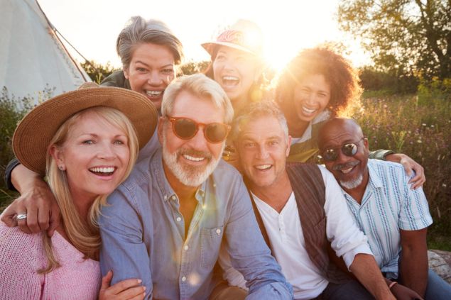Grupo com 7 amigos, formado por homens e mulheres sorridentes, posando para uma foto.