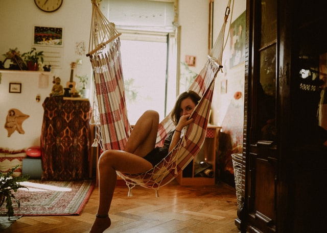 Mulher sentada numa rede em sua casa.