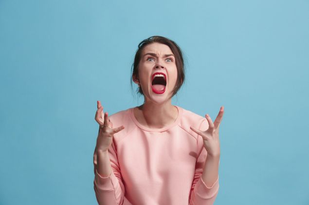 Mulher irritada esbravejando com as mãos e gritando.