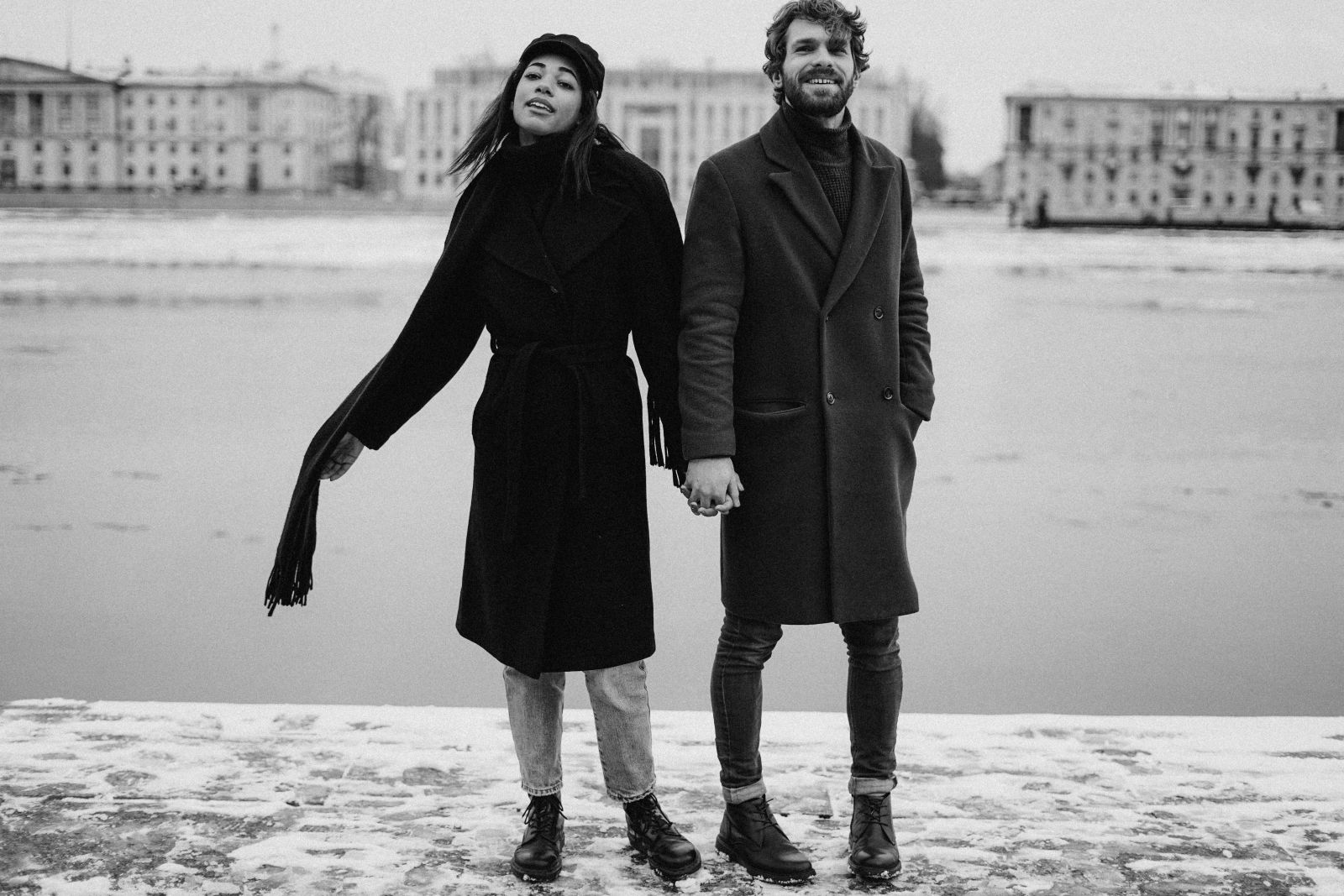 Homem e mulher lado a lado, com roupas de frio, em frente a um lago.