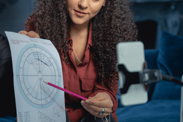 Mulher com um lápis na mão apontando para um Mapa Astral