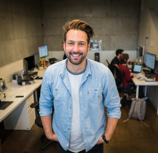 Homem em pé sorrindo em seu trabalho