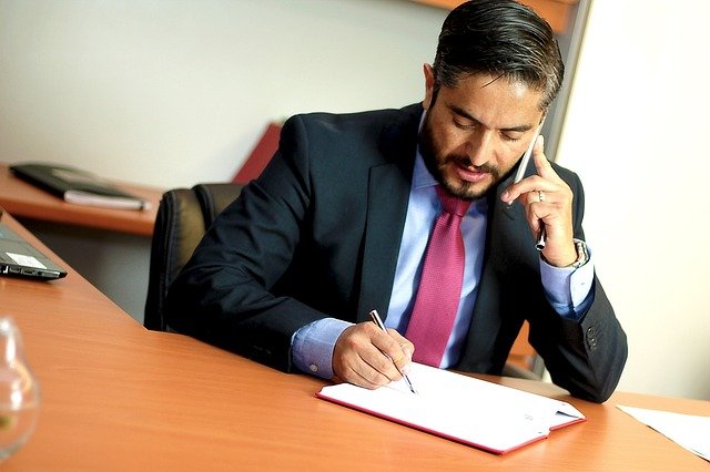 Advogado falando ao celular e anotando 