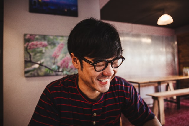 Homem asiático com expressão sorridente.