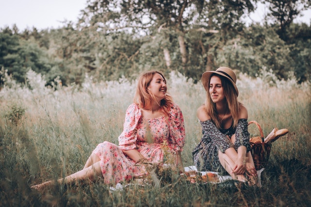 Mulheres brancas sentadas num campo.