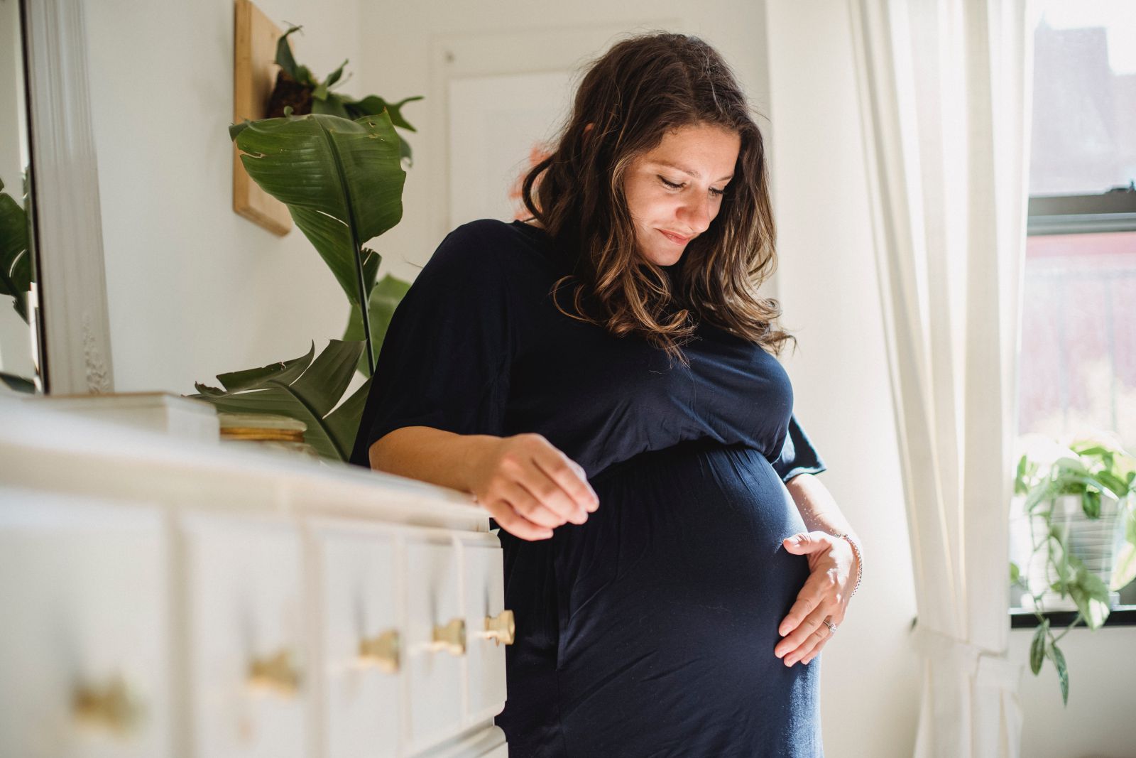 Mulher grávida sorrindo com a sua mão na barriga 