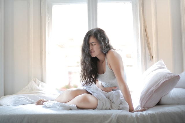 Mulher na cama com cólica